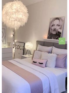 a bedroom with white and pink bedding, chandelier and pictures on the wall