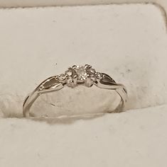 a white gold ring with three diamonds on it in a box that is open to show the inside