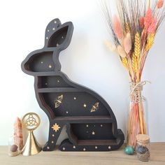 a wooden rabbit shaped shelf sitting on top of a table next to a vase filled with flowers