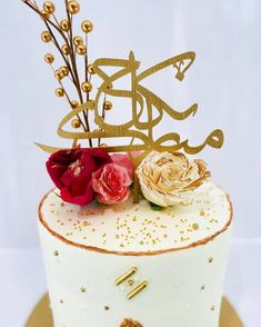 there is a white cake with gold decorations on it and some flowers in the middle