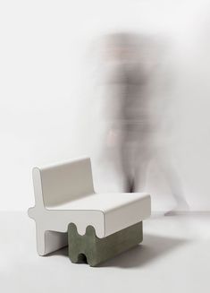 a blurry image of a person walking past a white chair