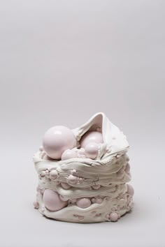 there is a white sculpture with pink balls in it's shell on the table