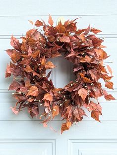 a wreath hanging on the side of a white door with red and green leaves around it