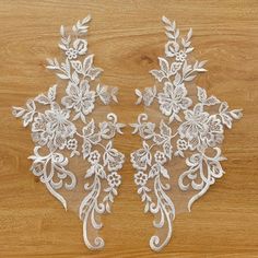 two white lace appliques on a wooden surface with wood flooring in the background