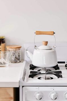 a white stove top with a tea kettle on it's burner in a kitchen