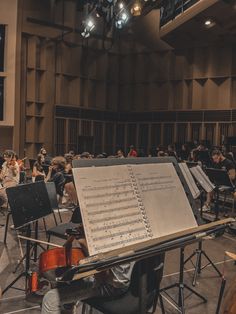 a group of people sitting in front of an orchestra with sheet music on the desk