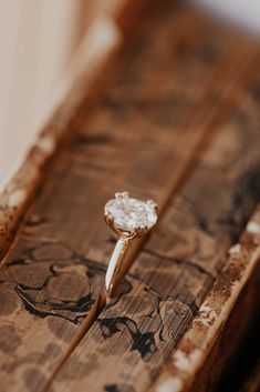 a diamond ring sitting on top of a piece of wood with no one around it