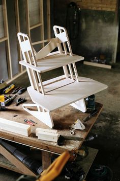 an unfinished chair sitting on top of a workbench in a room filled with tools