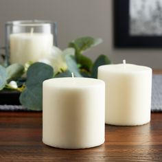 two white candles sitting on top of a wooden table