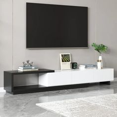 a living room with a large flat screen tv mounted on the wall and two planters in front of it