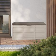 an empty storage box sitting on the side of a wooden deck next to a window