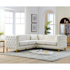 a living room with white couches and rugs on the floor, windows in the background