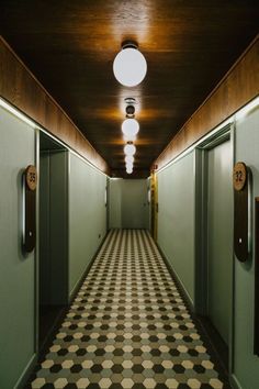 an empty hallway with two elevators and checkered floor