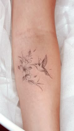 a woman's arm with flowers and a bird tattoo on the left side of her leg