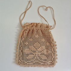 a small bag made out of crochet on a white surface with a string attached to it