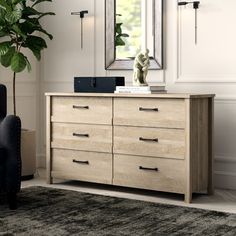 a dresser with drawers and a mirror above it in a room that has white walls