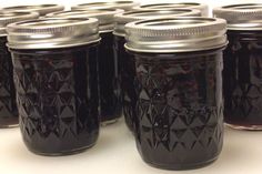 several jars filled with black liquid sitting on top of a white countertop next to each other