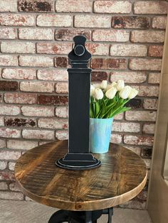 a vase with flowers sitting on top of a wooden table next to a brick wall