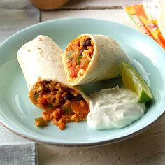 a burrito filled with beans and vegetables on a plate next to a lime wedge