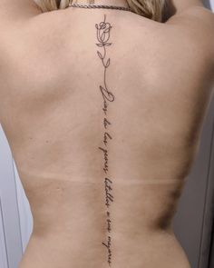 the back of a woman's body with writing on it and a rose tattoo