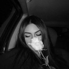 a woman sitting in the back seat of a car with a rose in her mouth