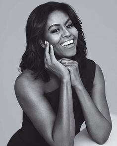 a black and white photo of a smiling woman with her hands on her chins