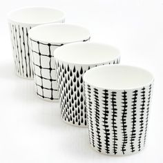 four black and white cups sitting next to each other on top of a white surface