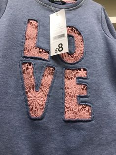 a blue shirt with the word love written in pink lace on it's chest