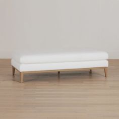 a white bench sitting on top of a hard wood floor next to a white wall