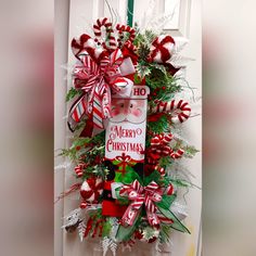 a christmas wreath hanging on the front door with candy canes and bows around it