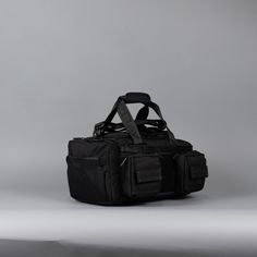 a black duffel bag sitting on top of a white table next to a gray wall