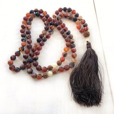 "Mala For Acceptance -Matte Dream Agate Beads Accented With Yellow Jade & Rudraksha - 108 Mala Bead Necklace - Hand Knotted - 8mm & 6mm Beads Length 36.5\" Gently release the body and the mind with this earthy Dream Agate Mala necklace from True Nature Jewelry. It features Dream Agate for grounding and centering along with Rudraksha and Jade in a free-spirited display of design. Each bead is expertly hand knotted for durability. The addition of Rudraksha brings clarity and peace of mind Adjustable Agate Mala With 8mm Beads, Beaded Agate Mala With Round Beads, Adjustable Agate Mala With Round Beads, Handmade Agate Mala For Meditation, Adjustable Agate Hand-strung Mala, Adjustable Hand-strung Agate Mala, Brown Mala With Natural Stones And Round Beads, Brown Mala With Natural Round Beads, Brown Mala With Natural Stones