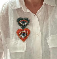 a person wearing a white shirt with two heart shaped patches on the chest and an eye patch in the middle