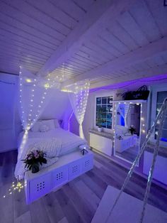 a white bed sitting in a bedroom next to a window with purple lights on it