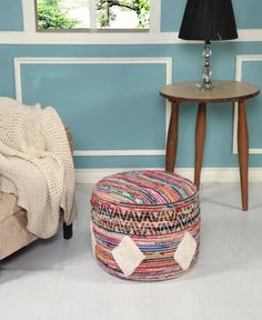 a living room with blue walls and a round foot stool next to a small table