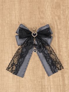 a black and grey bow with lace on it sitting on a wooden table next to a wall