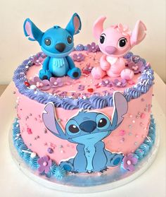 a pink and blue cake with two small figurines sitting on top of it