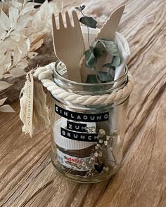 a glass jar filled with wooden utensils sitting on top of a wood table