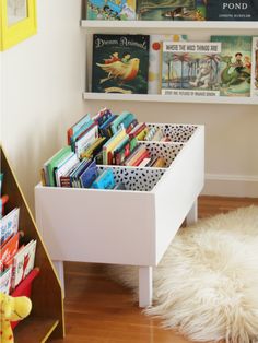 there is a book shelf with books on it and a white rug in the corner