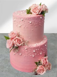 a three tiered pink cake with flowers on it's side and pearls around the edges