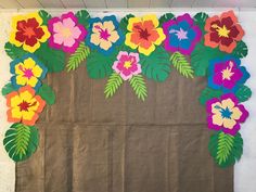 a piece of brown paper with colorful flowers on it and leaves around the edges, in front of a white wall