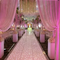 an aisle decorated with pink flowers and white draping for a wedding or reception