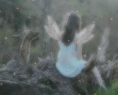 a fairy sitting on top of a tree stump in the woods with her wings spread