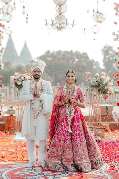 two people standing next to each other in front of flowers and chandelier hanging from the ceiling