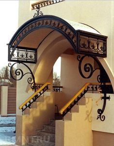 an arched entrance to a building with stairs and railings on either side, in the snow