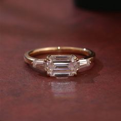 an engagement ring with three baguettes on it sitting on top of a table