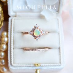 an opal and diamond ring sits in a white velvet box with pearls surrounding it