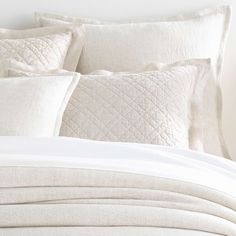 a bed with white linens and pillows on it