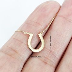 This stunning horseshoe gold necklace is a perfect symbol of good luck and charm. The pendant is crafted from high-quality 14k gold and features a beautifully designed horseshoe with intricate detailing that catches the eye. The pendant hangs on a dainty yet sturdy gold chain that complements the pendant's design, creating an elegant and timeless piece of jewelry. This necklace is perfect for adding a touch of equestrian style to any outfit, and is a must-have for any horse lover, cowgirl, or co Horseshoe-shaped Jewelry With Adjustable Chain, Gold Horseshoe Jewelry With Adjustable Chain, 14k Yellow Gold Horseshoe Jewelry, 14-karat Yellow Gold Horseshoe Jewelry, Gold Horseshoe Necklace With Adjustable Chain, Gold Initial Pendant Necklace For Good Luck, Good Luck Horseshoe Charms Jewelry, Minimalist Personalized Good Luck Necklace, Gold Horseshoe Necklace For Good Luck