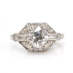 A perfect Art Deco engagement ring. A 1.75 ct Old European Cut diamond (G VS2) is flanked on either side by a baguette diamond (0.14 ct total, F VS1). The entire ring is outlined by 0.30ct of F VS2 round diamonds, bringing the total carat weight to 2.19 ct. The ring is made of platinum. We must say, it is rare to find a high color, high clarity stone and have it be an old fashioned cut. When the modern brilliant first arrived, a lot of people took their good diamonds and had them recut in an eff Timeless Octagon Platinum Diamond Ring, Classic Octagon Diamond Ring With Single Cut Diamonds, Classic Octagon Diamond White Diamond Ring, Octagon Platinum Diamond Ring With Single Cut Diamonds, Platinum Octagon Brilliant Cut Wedding Ring, Octagonal Diamond Ring With Center Stone, Classic Octagon Platinum Diamond Ring, Timeless Octagon Diamond Ring With Center Stone, Classic Gia Certified Baguette Cut Diamond Ring